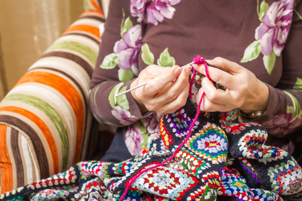Hands of woman knitting a vintage wool quilt